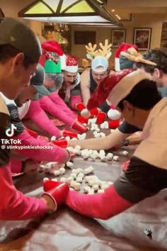 several people in santa hats are playing with marshmallows