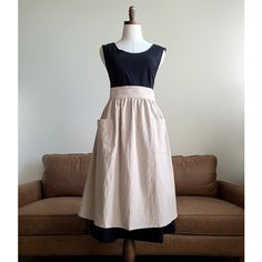 a dress on a mannequin in front of a couch with a brown sofa behind it