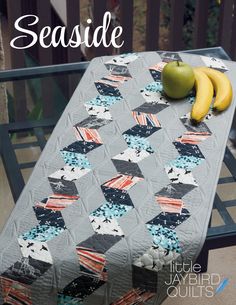 there is a quilt on the table with two bananas and an apple next to it