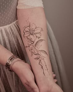 two women holding hands with tattoos on their arms and the arm is covered in flowers