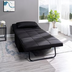 a black futon bed sitting on top of a wooden floor next to a window