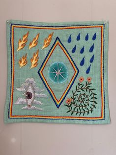 an embroidered wall hanging with different designs and colors on the front, including leaves, flowers, and raindrops