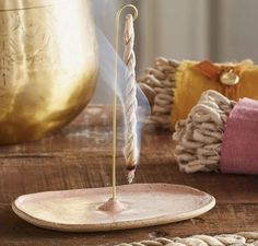 a candle that is on top of a wooden table next to some rope and pillows