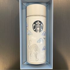 a starbucks cup in a blue box with an elephant and zebra design on the lid