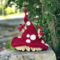 a crocheted mushroom hat sitting on top of a rock next to a tree