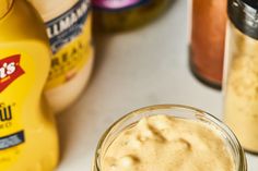 a glass jar filled with peanut butter next to bottles of mustard and ketchup