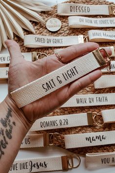 a person holding onto some white and gold keychains with words on them that read salt and light