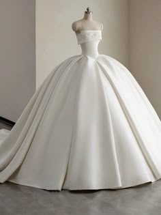 a white ball gown on display in a room with a mannequin headpiece