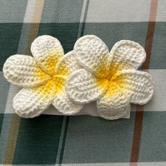 a crocheted flower on top of a checkered table cloth with yellow center