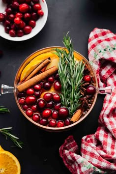 a bowl filled with cranberries, oranges and cinnamon on top of a table