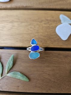 a ring with blue glass sitting on top of a wooden table next to green leaves