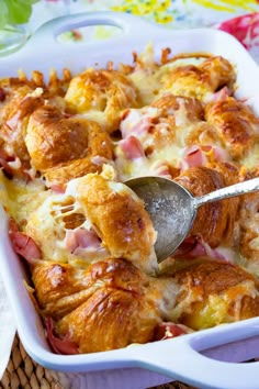 a casserole dish with ham and cheese in it being spooned into the casserole