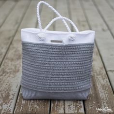 a gray and white bag sitting on top of a wooden floor next to a rope