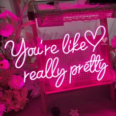 a pink neon sign that says you're like really pretty with flowers in the background