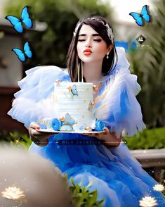 a woman in blue dress holding a cake with butterflies flying around her and looking at it