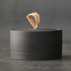 a piece of bread that has been placed on top of a black container with a rope sticking out of it