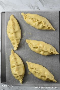 four uncooked dumplings on a baking sheet