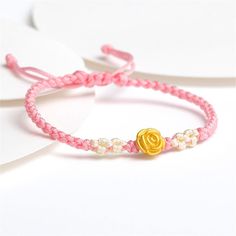 two pink and white bracelets with a gold rose on it, sitting next to each other