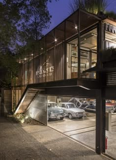 an outside view of a building with cars parked in the parking lot and lights on