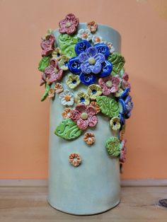 a ceramic vase with flowers and leaves painted on the outside, sitting on a table