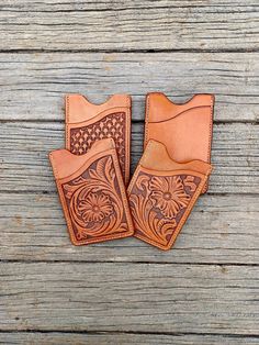 two leather wallets sitting on top of a wooden table