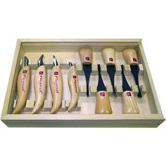 an assortment of wood carving tools in a wooden display case on a white background,