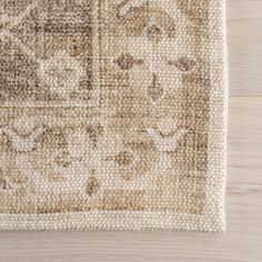 an area rug on top of a wooden floor with a white and brown color scheme