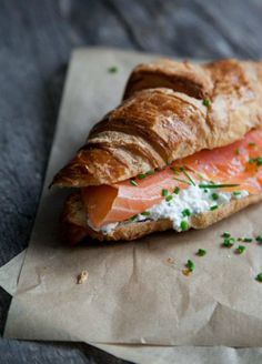 a bagel with salmon and cream cheese on it sitting on top of a piece of wax paper