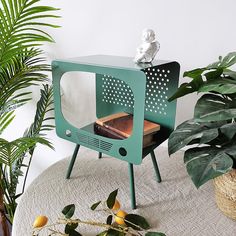 an old fashioned television sitting on top of a table next to a potted plant