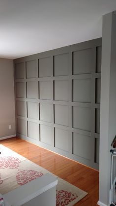 an empty room with wooden floors and gray doors on the wall, in front of a carpeted area