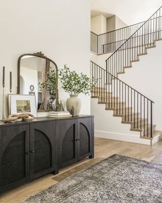 a living room with a large rug and stairs