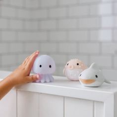 two small plastic animals sitting on top of a white radiator next to a person's hand