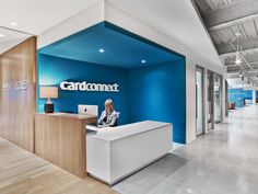 a woman sitting at a desk in front of a blue wall with the word cardoneat on it