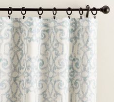 the curtain is hanging on the rod in front of the window, with an ornate pattern