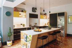 a kitchen with wooden floors and white counter tops next to an open concept dining area