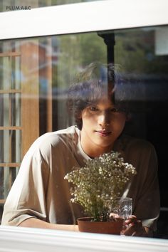 a woman sitting at a window sill with a potted plant in front of her