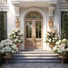 two large vases filled with white and pink flowers sitting in front of a door