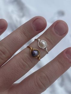 a woman's hand with three rings on it, one is gold and the other is silver