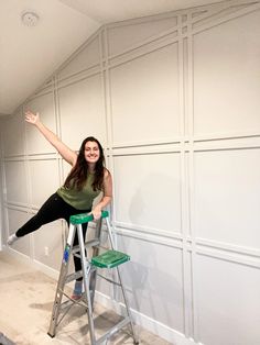 a woman is sitting on a stepladder and posing with her arms in the air