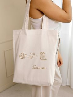 a woman holding a white bag with gold lettering