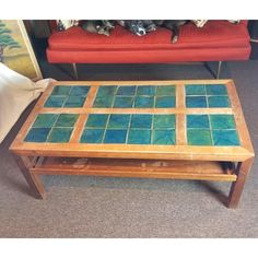 a coffee table with blue and green tiles on it in front of a red couch