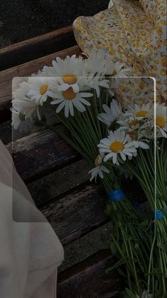 daisies and other flowers are sitting on a bench