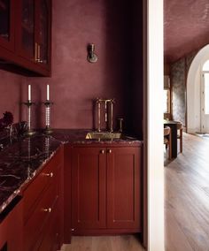 a kitchen with red cabinets and marble counter tops