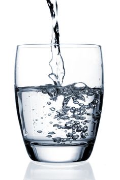 water being poured into a glass filled with liquid