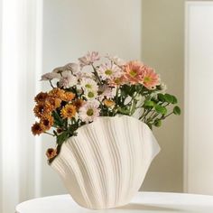 a white vase filled with lots of different colored flowers on top of a round table