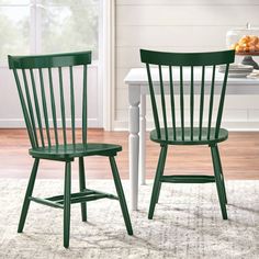 two green chairs sitting next to each other on top of a rug