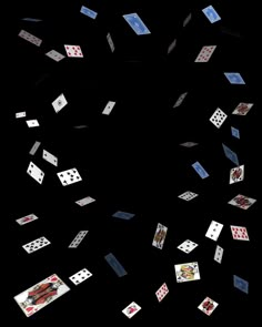 many playing cards are flying in the air on a black background with white and blue squares