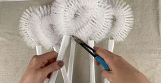 a person is using scissors to cut out the top of a white flower with fringes