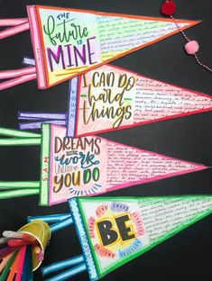 colorful paper pennants with writing on them are hanging from a blackboard background and decorated with colored pencils