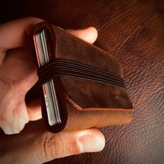 a hand holding a brown wallet on top of a table